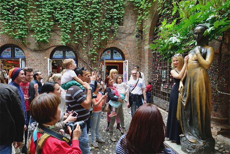 Tourists near Juliet statue in Verona, Italy. The Juliet statue is one of most popular and symbolic tourist attraction in Verona, Italy — Photo by _fla