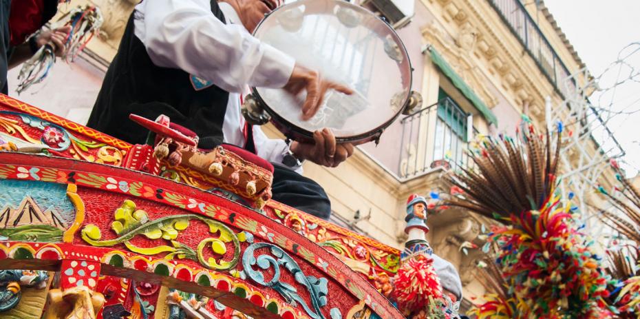 Close up view of a colorful wheel of a typical sicilian cart and a folkloristic tambourine player on it. Copyright : Marco Ossino